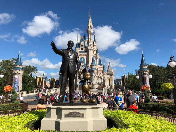 Walt Disney and Mickey Mouse standing outside Cinderella's castle