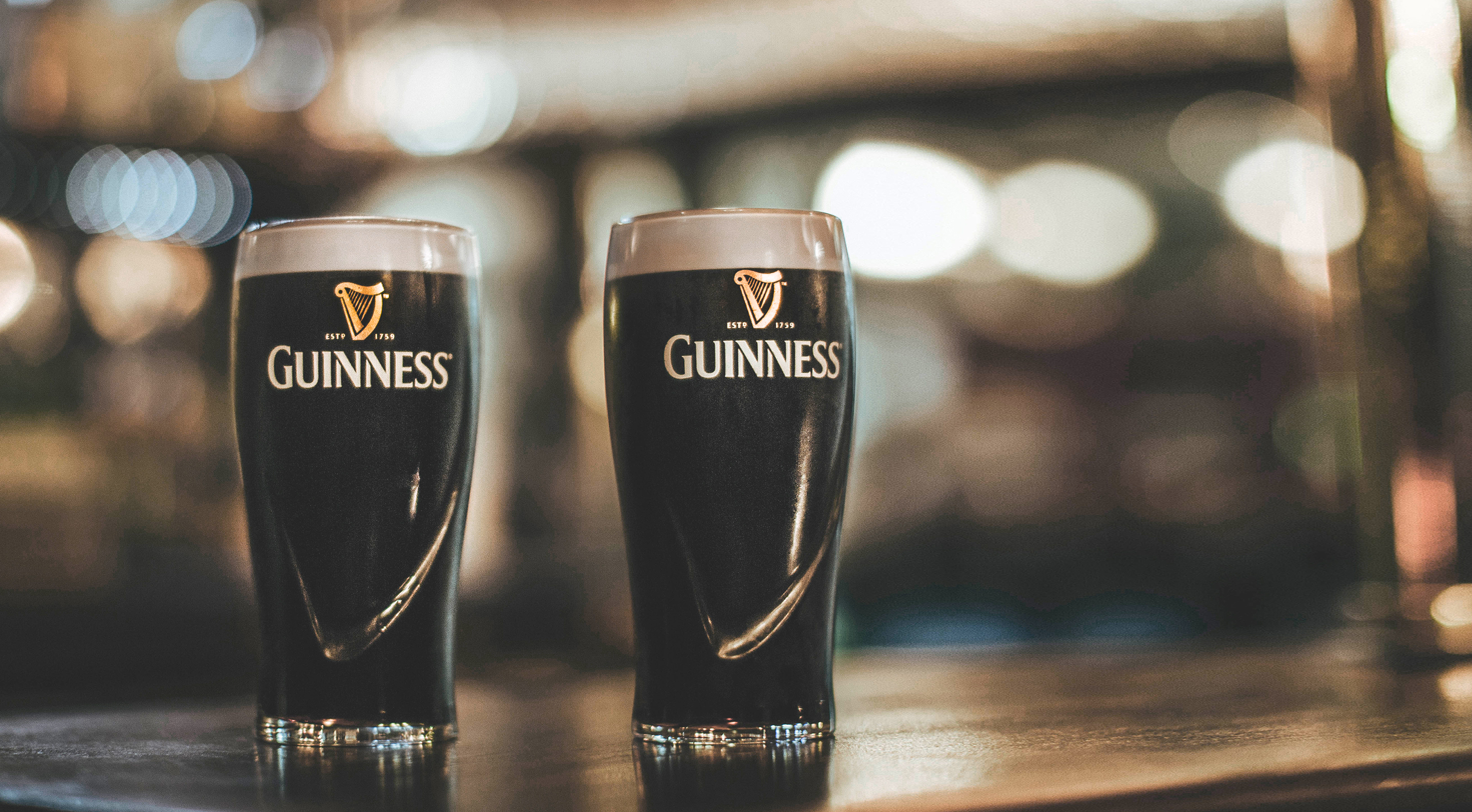 Two pints of Guinness on a bar
