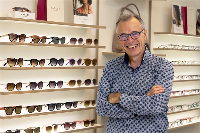Inspecs chief executive standing in front of a shelf of glasses 